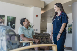 Smiling patient speaks with a healthcare professional in a clinic waiting room.